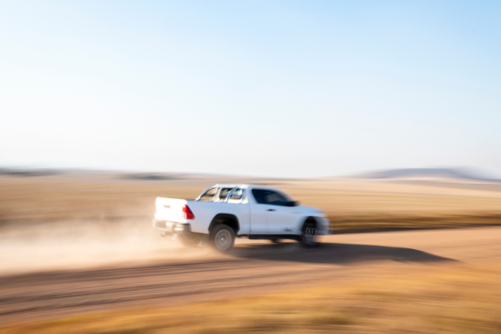 White Toyota truck driving very fast through the desert road