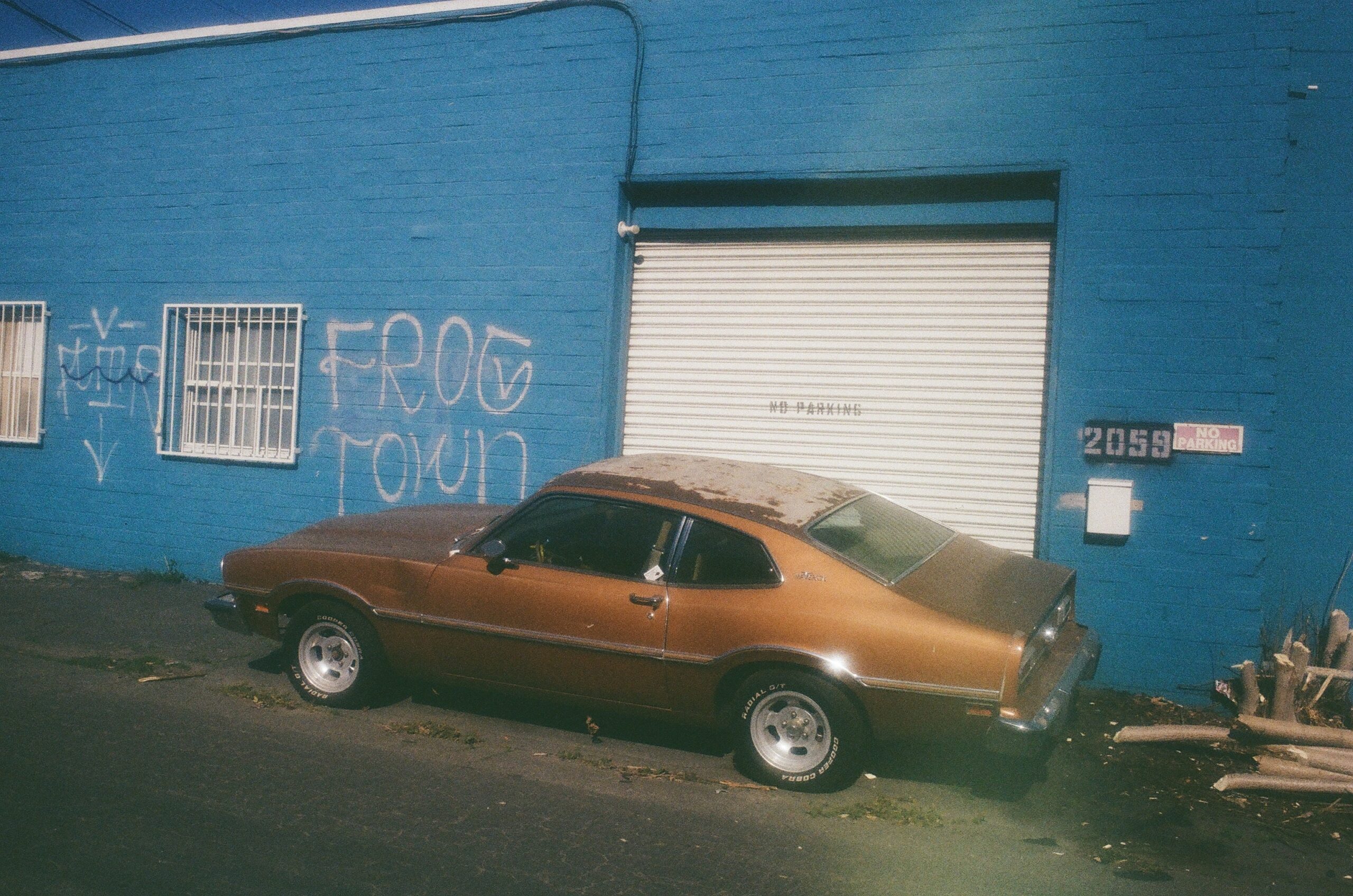 Car from 1980 is parked near the blue wall
