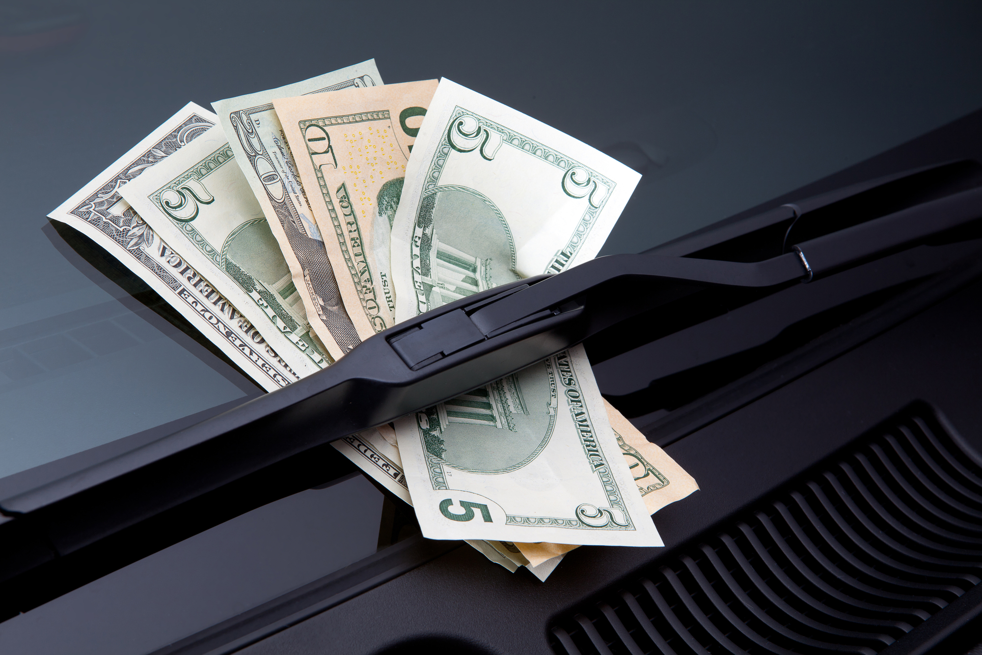 Dollar bills under windshield wipers, close up