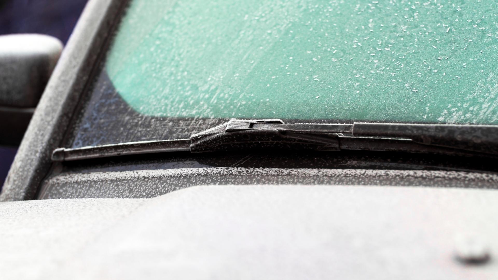 Close up photo on completely iced car's windshield, wiper blade is also covered with ice. Big image