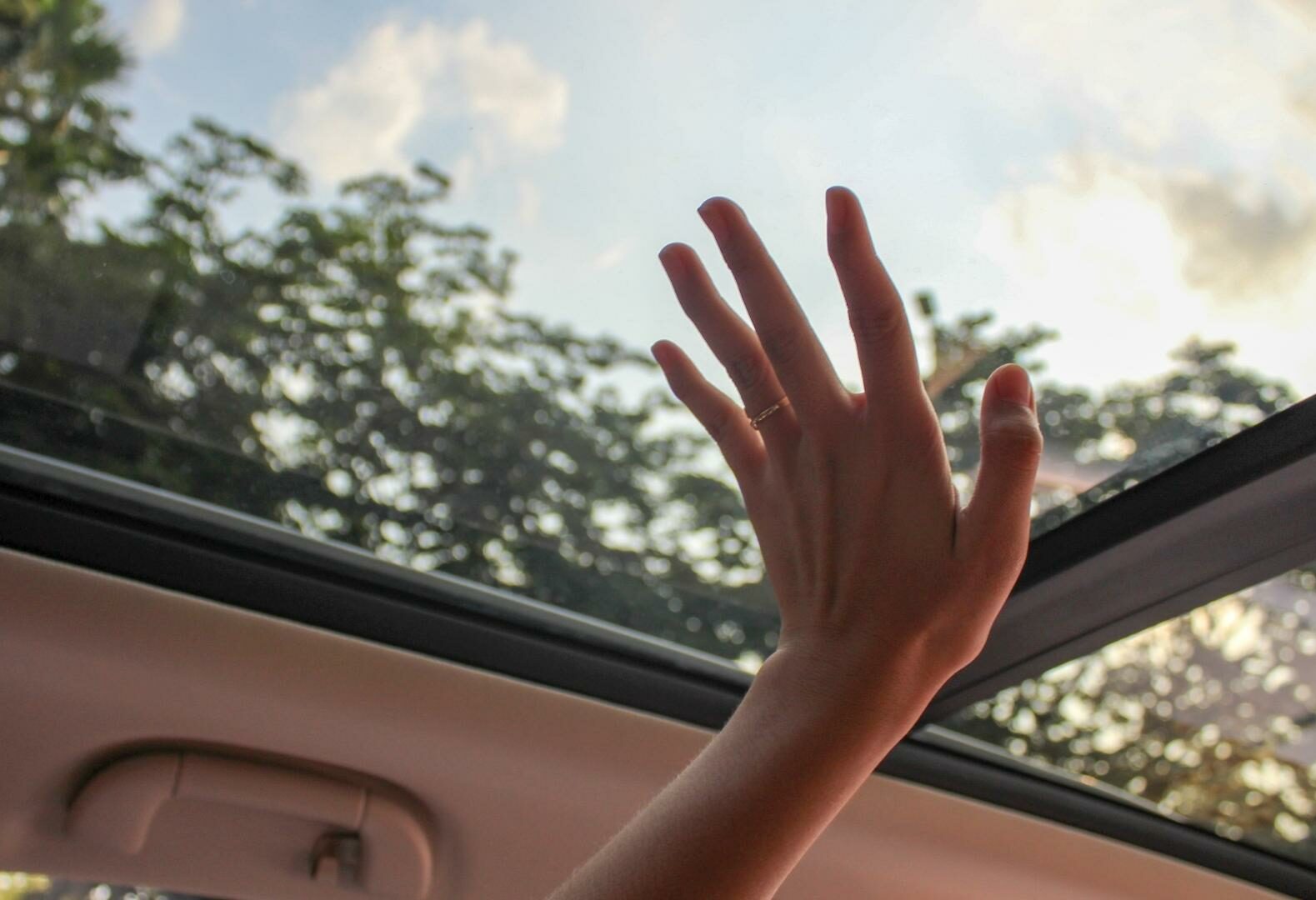 Hand tries to reach cars glass roof, view from inside the car