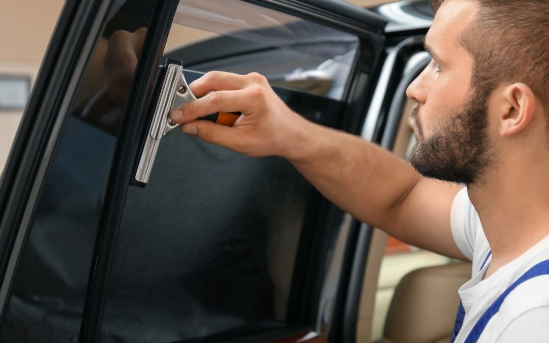 Auto glass technician is tinting car's rear side window
