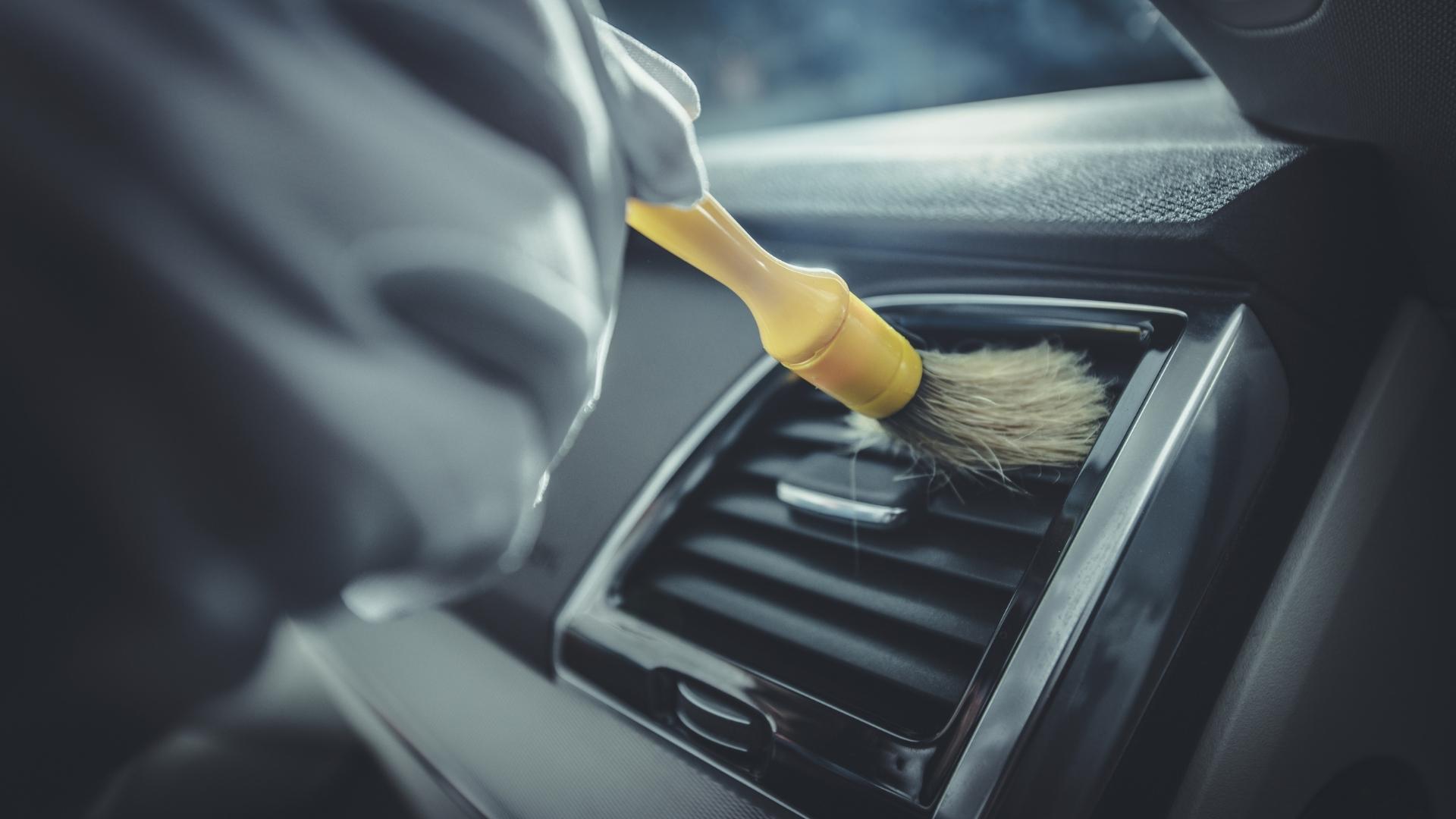 Car detailing close up, person in cleaning air channels with brush